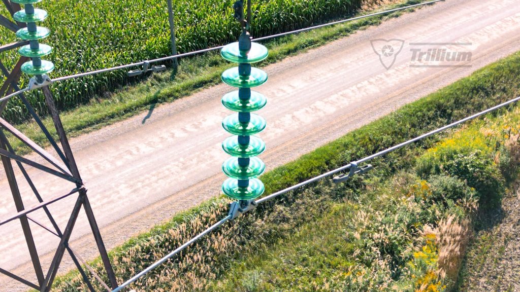 Close-up aerial view of power line infrastructure over a rural road and farmland in Ontario, captured by Trillium Imaging's drone services.