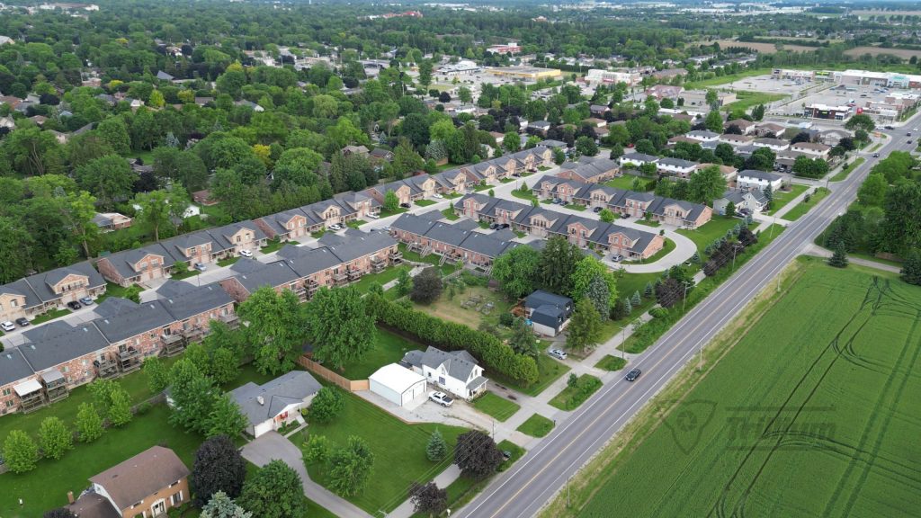 Aerial view of a residential neighborhood in Stratford, Ontario, with green trees and nearby roads.