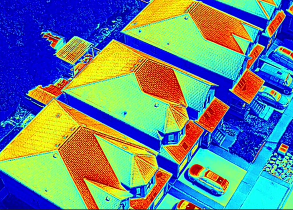 Aerial Thermal Scan of Residential Rooftops Thermal drone image of residential rooftops showing heat loss patterns in varying colors.