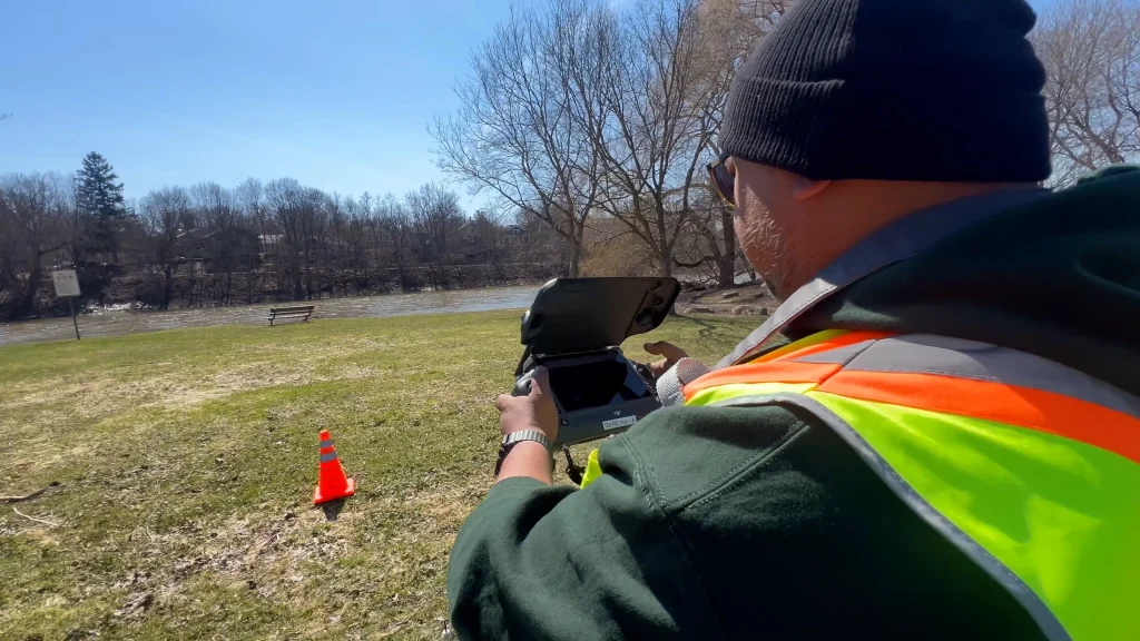 Drone pilot conducting aerial site mapping near a নদ river in Ontario using professional UAV equipment